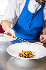 Obraz na płótnie Canvas Chef prepara setas de temporada salteadas con yema de huevo curada con salsa de soja y flores decorativas sobre un plato de loza blanco