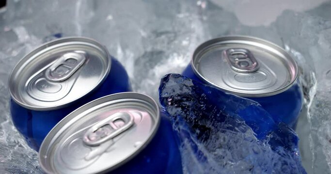 The drink is cooled with ice in a metal can. Beer in aluminum cans was placed in ice. Pieces of ice fall into a container with drinks.