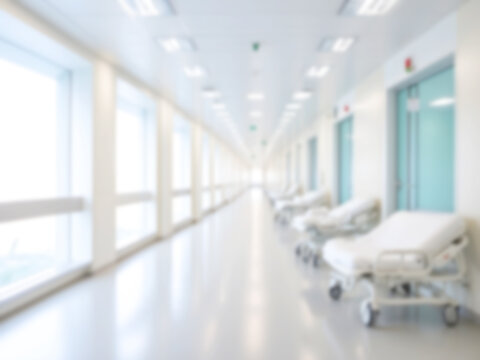Blurred image of hospital corridor interior, white medical beds on the side, empty corridor, bright light. Medical and healthcare concept.