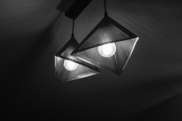 Black and white hanging dangling triangle ceiling lamp in front of a dark background