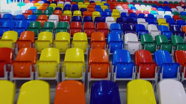 Searchlight spots move by empty colorful chairs in Megasport sports palace