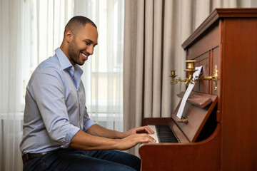 Man practicing playing piano in living room of his home relaxing from work