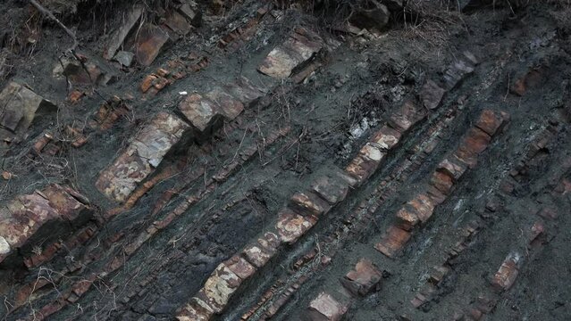 Cliff - rugged dipping sedimentary rock mountain formation. Vertical natural rough wall of stratum layers, jagged, sliced and cracked.