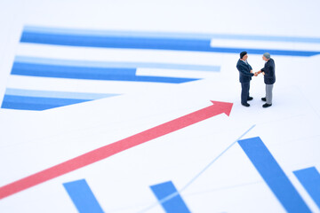 Miniature Businessmen Handshake on Growth Chart with Upward Arrows