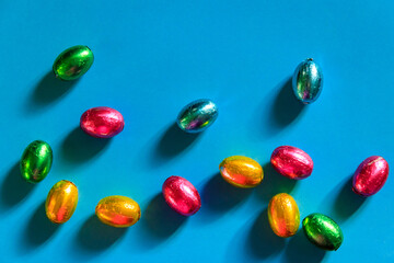 Easter chocolate eggs in foil on blue background. Top view