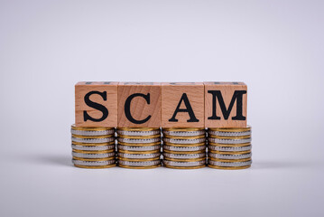 The inscription Scam made of wooden cubes on a plain background