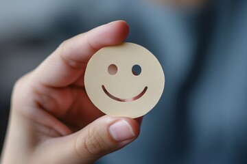 Hand holds paper cut smile face, symbolizing positive thinking, mental health assessment. Perfect for World Mental Health Day concept.