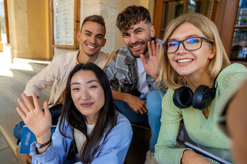 Students making selfie together while sitting on stairs in university campus.