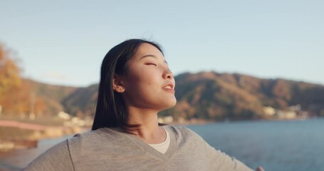 Japanese woman, freedom and peace outdoor, lake or ocean with travel, holiday and mindfulness in nature. Wellness, adventure and care free at beach in Japan, happy with breathing and positivity