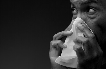 cold and flu blowing nose after catching the flu with grey black background with people stock image stock photo	