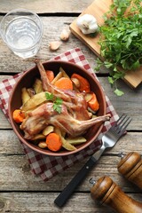Tasty cooked rabbit with vegetables served on wooden table, flat lay
