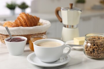 Breakfast served in kitchen. Fresh coffee, granola, croissants, jam and honey on white table