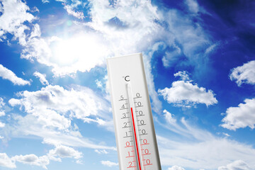 Thermometer showing high temperature against sky with clouds in summer