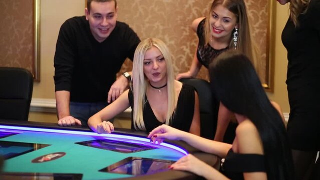 Five young people stand and sit by electronic poker table