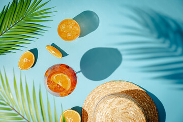 Summer refreshing cocktail aperol spritz with orange and palm leaves on a blue background with...