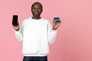Cheerful black man wearing white sweatshirt showing phone with blank screen and credit card