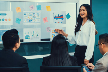 A female leader presenting growth Statistics with confident in front of whiteboard rounded by...