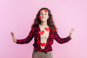 Portrait of happy cheerful teenage girl with wavy hair in red checkered shirt standing covered with...