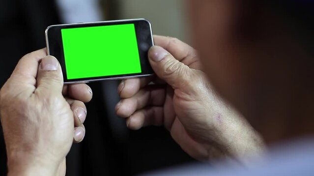An Unrecognizable Senior Man Using A Cellphone Green Screen. Close Up. You can replace green screen with the footage or picture you want with “Keying” effect in After Effects.