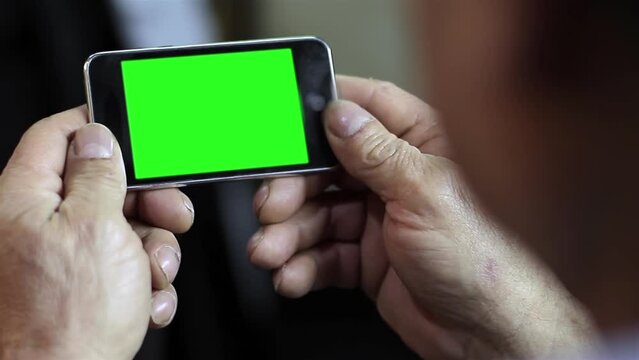 An Unrecognizable Senior Man Using A Cellphone Green Screen. Close Up. Zoom Out. You can replace green screen with the footage or picture you want with “Keying” effect in After Effects.