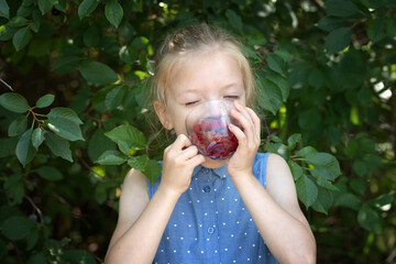 A little girl eats raspberries in the garden. The concept of healthy natural food. Close-up portrait.