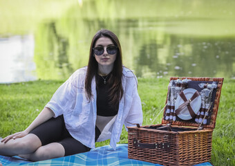 Young brunette girl at a picnic in the park by the lake.
