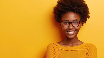 Obraz premium Radiant young woman with glasses and afro smiling on a bright yellow background