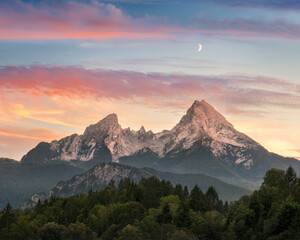 A majestic mountain formation, the Watzmann in Bavaria, Germany, with a colorful sunset sky and woodlands in the foreground