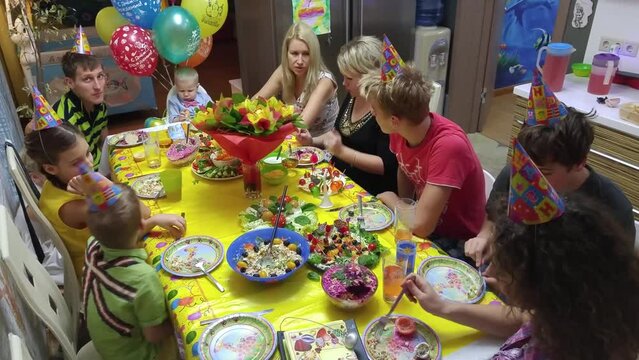 Seven adults and children on baby birthday at table