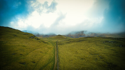 Misty hills with a narrow path under a dramatic sky