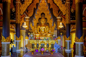 Yellow golden Buddha statue in the hall, Buddhist temple houses the Buddha’s relics, Wat Phra That Doi Prachan located in the district of Mae Tha, Tourist attraction in Lampang, Northern of Thailand.