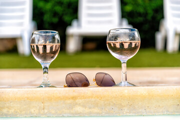 glasses of white wine beside a swimming pool