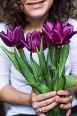 Purple tulips in hands natural on white t-shirt spring flowers warm background
