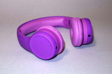 Purple headphones on a grey background.