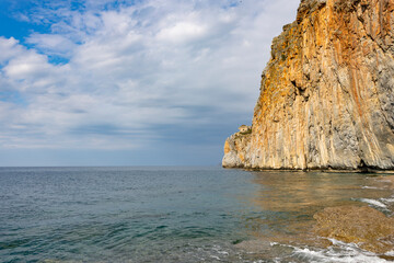Fototapeta na wymiar rock in the sea, a steep cliff leading into the sea, illuminated by the sun