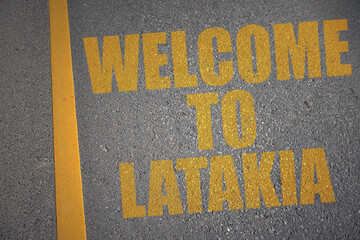 asphalt road with text welcome to Latakia near yellow line.