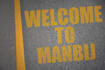 asphalt road with text welcome to manbij near yellow line.