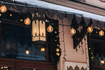 Street lamp and garland with vintage lamps on the facade of a cafe in Lviv, Ukraine. Decoration on the facade near the store window.