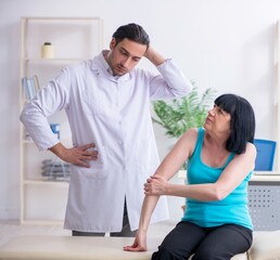 Fototapeta premium Young male doctor examining old female patient