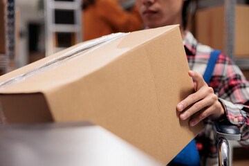 Warehouse worker using wheelchair while holding cardboard box in hands. Storehouse order handler...