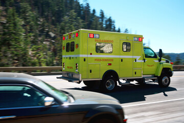 A Yellow Fire Rescue Paramedic First Responder Ambulance with emergency lights flashing passing...