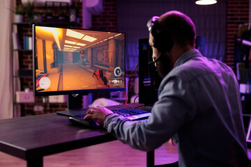 Experienced gamer competing in intense online multiplayer videogame, broadcasting esports tourney live from brick wall apartment. Man using expert level gaming mouse and keyboard, preventing input lag