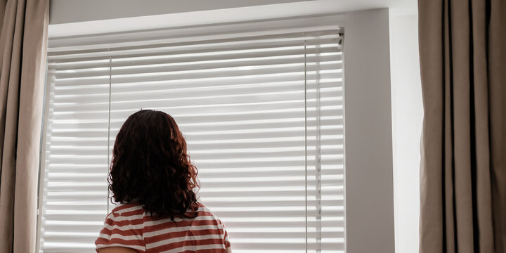 Woman Looking Out of Window Blinds