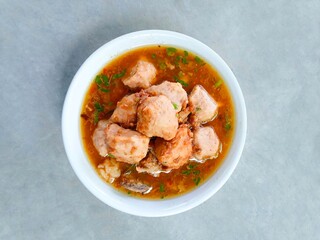 bakso, meatballs served in a bowl on a gray background. Meatball soup with marrow, chicken bones and spring onions without noodles or vermicelli. savory and delicious soupy food. Top view