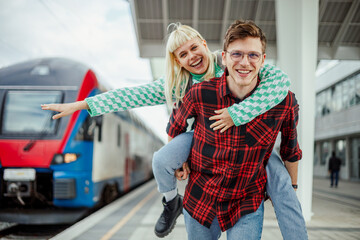 Portrait of an urban couple having piggyback ride at train station.