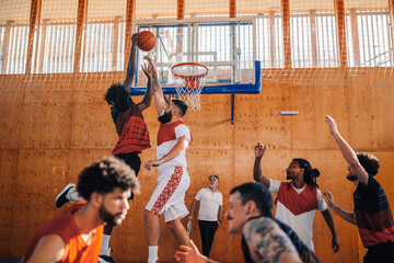 Interracial basketball player dunking the ball on his training. - obrazy, fototapety, plakaty