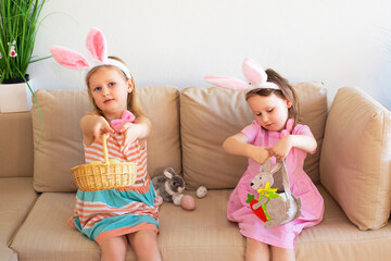 children in bunny clothes sitting on the sofa at home and watching Easter eggs