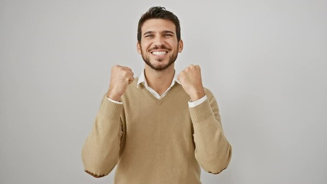 Victorious! excited young hispanic man wearing sweater, triumphantly screaming in joy, arms raised in celebration of success. standing proud, isolated on white background.