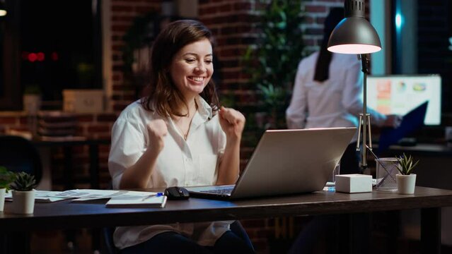 Woman in office celebrating finalizing deal with business partners, happy about incoming salary bonus. Employee in workplace dancing on chair after closing agreement with B2B clients, camera B