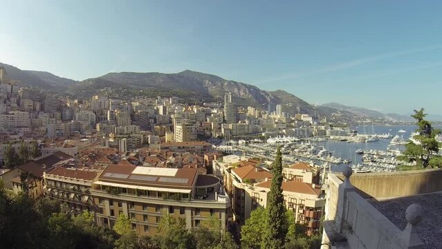 Port Monaco with ships near buildings and mountains on sunny day. 